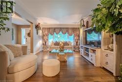 Spacious living area featuring wood-finish flooring, a decorative window with valance and drapes, and a built-in media console with cabinet storage - 
