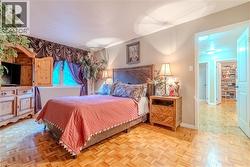 Parquet wood-finish flooring in a bedroom featuring a window with purple drapery - 