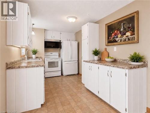 VIRTUALLY STAGED. Kitchen featuring white cabinetry, stone-look laminate countertops, and a full suite of white appliances including a refrigerator, range, and microwave - 162 Tiffany Street, Cambridge, ON - Indoor Photo Showing Kitchen