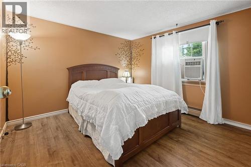 Room featuring wood-finish flooring, a window with an air conditioning unit, and baseboard heating - 162 Tiffany Street, Cambridge, ON - Indoor Photo Showing Bedroom