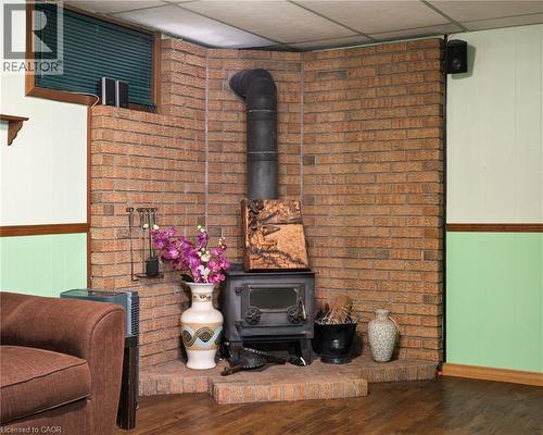 Brick corner fireplace with a black wood-burning stove on a raised brick hearth - 162 Tiffany Street, Cambridge, ON - Indoor With Fireplace