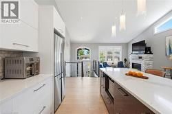 Modern kitchen featuring white cabinetry, a stainless steel refrigerator, and a large center island with a white countertop - 