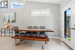 Spacious dining area featuring wood-finish flooring, a contemporary chandelier, a transom window, and a full-light exterior door - 