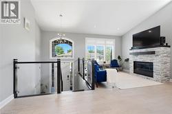 Spacious room featuring light wood-finish flooring, a contemporary fireplace with stacked stone surround, and an arched window - 