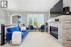 Spacious living area featuring a stacked stone fireplace with a floating mantel, an arched window, and recessed lighting - 