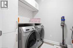 Dedicated laundry area featuring a front-loading washer and dryer set, white cabinetry, a white countertop, and subway tile backsplash - 