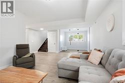 Lower-level living area featuring wood-finish flooring, recessed lighting, and a window with horizontal blinds - 