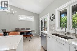 Contemporary kitchen featuring white cabinetry, quartz countertops, a stainless steel dishwasher, a double basin sink with gooseneck faucet, and a subway tile backsplash - 