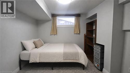 Carpeted room featuring a built-in wooden shelving unit, a single window with natural light, and a flush-mount ceiling light fixture - 10 Doll Court, Kitchener, ON - Indoor Photo Showing Bedroom