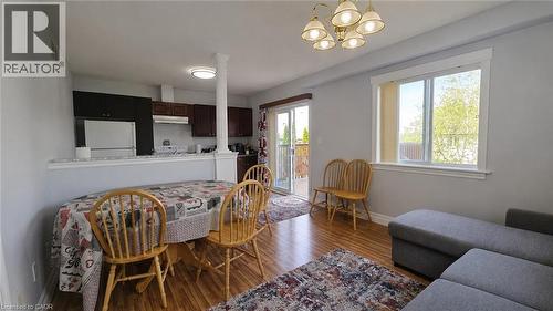 Open-concept living area featuring wood-finish flooring, light grey walls, and a recessed kitchen with dark cabinetry - 10 Doll Court, Kitchener, ON - Indoor Photo Showing Dining Room