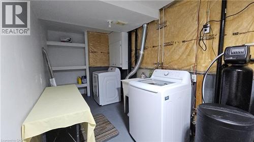 Dedicated laundry area featuring a utility sink, built-in shelving, two appliances, and a water treatment system - 10 Doll Court, Kitchener, ON - Indoor Photo Showing Laundry Room
