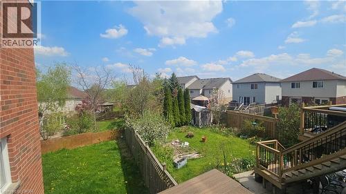 Expansive outdoor space featuring a multi-level wood deck with black metal balusters, a grassy lawn area, and mature perimeter trees - 10 Doll Court, Kitchener, ON - Outdoor