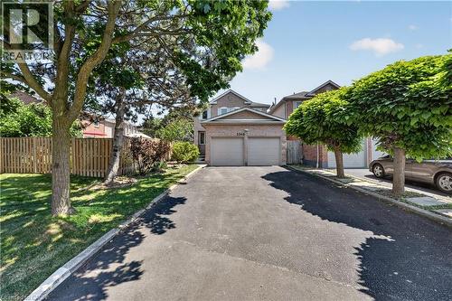 Brick two-story residence featuring a two-car garage with individual doors, a paved driveway, and mature landscaping - 3346 Chartrand Crescent, Mississauga, ON - Outdoor