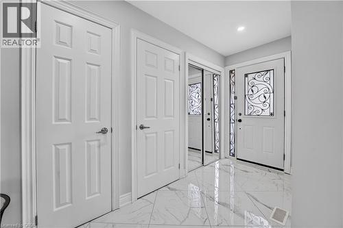 Foyer featuring high-gloss marbled tile flooring, a white paneled entry door with decorative ironwork, and mirrored closet doors - 3346 Chartrand Crescent, Mississauga, ON - Indoor Photo Showing Other Room