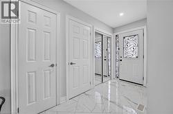 Foyer featuring high-gloss marbled tile flooring, a white paneled entry door with decorative ironwork, and mirrored closet doors - 