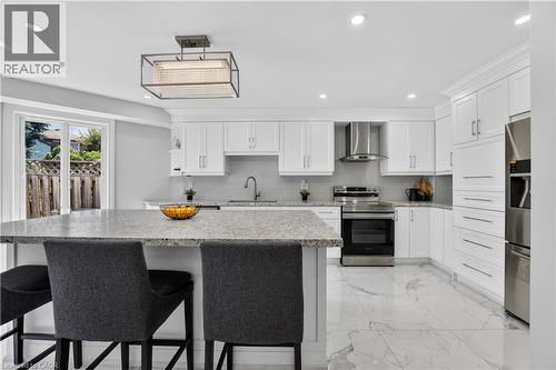 Bright kitchen featuring white shaker cabinetry, stainless steel appliances, speckled stone countertops, and a full tile backsplash - 3346 Chartrand Crescent, Mississauga, ON - Indoor Photo Showing Kitchen With Upgraded Kitchen