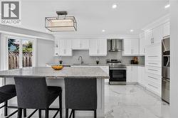Bright kitchen featuring white shaker cabinetry, stainless steel appliances, speckled stone countertops, and a full tile backsplash - 
