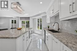 Spacious kitchen featuring white cabinetry, light-toned granite countertops, and a white subway tile backsplash - 