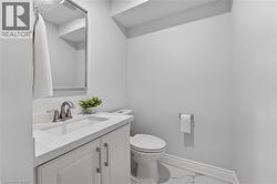 White vanity with panel cabinetry and brushed nickel hardware, integrated sink, and coordinating countertop - 