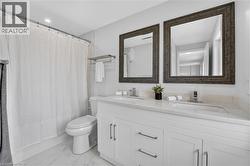 Double vanity with white cabinetry, under-mount sinks, and light-toned countertops - 