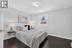 Bedroom featuring dark wood-finish flooring, light grey walls, and white trim - 