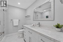 Bathroom featuring a spacious white vanity with an integrated sink, a large framed mirror, and a glass-enclosed shower with white marble-style wall tiling - 