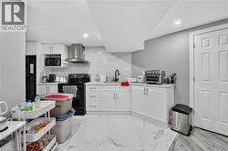 Bright kitchen area featuring white shaker-style cabinetry, a white countertop, and a white subway tile backsplash - 