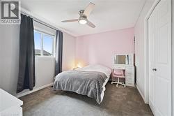 Bedroom featuring a white framed window, plush gray carpet flooring, and a ceiling fan with integrated lighting - 