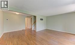 Spacious living area featuring wood-finish flooring, light green walls, and white trim - 