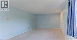 Carpeted interior space with light blue walls and white baseboards - 