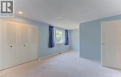 Carpeted interior space featuring light blue walls, two windows, and recessed lighting - 