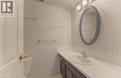 Bathroom vanity featuring a white countertop with an integrated sink, brushed chrome faucet, and dark wood-finish cabinetry - 