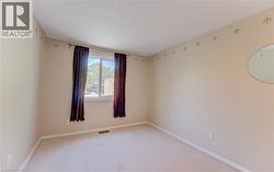 Carpeted interior space featuring neutral wall tones, a double window with drapes, and a decorative wall border - 