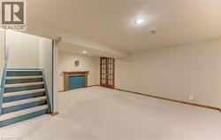 Carpeted room featuring a built-in fireplace with a carved wood mantel, recessed lighting, and double French doors with grid-patterned glass - 