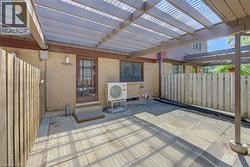 Private patio featuring a wood privacy fence, concrete paver flooring, and a translucent covered pergola - 