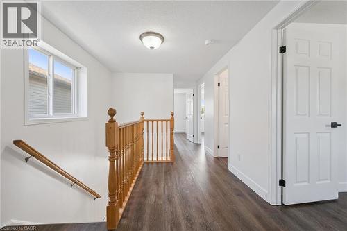 Upper-level hallway featuring wood-finish flooring, white walls, and multiple paneled doors with black hardware - 71 Peach Blossom Crescent, Kitchener, ON - Indoor Photo Showing Other Room