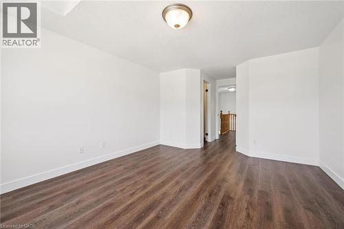 Spacious room featuring wood-finish flooring, white baseboards, and neutral wall paint - 71 Peach Blossom Crescent, Kitchener, ON - Indoor Photo Showing Other Room