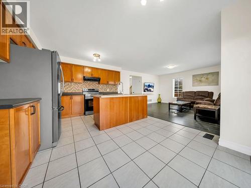 Kitchen featuring wood cabinetry, stainless steel appliances, a tiled backsplash, and a central island with a light-colored countertop - 39 Baintree Way, Cambridge, ON - Indoor Photo Showing Kitchen