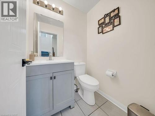 Bathroom featuring a light gray vanity with a white countertop and rectangular sink, a wall-mounted mirror, a four-light fixture, and light-toned floor tiles - 39 Baintree Way, Cambridge, ON - Indoor Photo Showing Bathroom