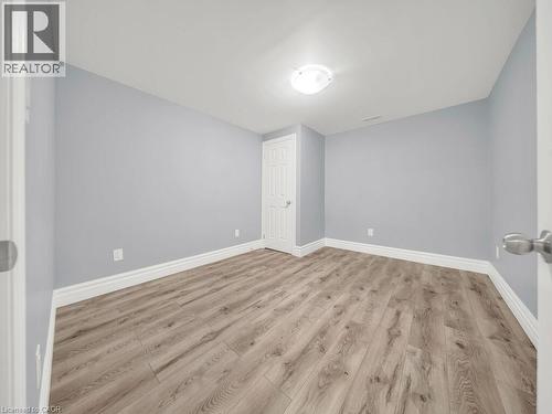 Spacious room featuring wood-finish flooring, light blue wall paint, white trim, and a flush mount ceiling light fixture - 39 Baintree Way, Cambridge, ON - Indoor Photo Showing Other Room
