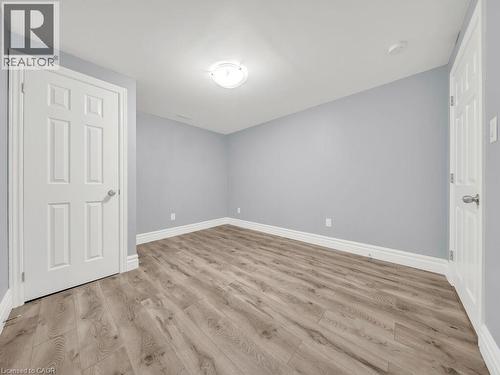 Spacious room featuring wood-finish flooring, light blue walls, white trim, and a flush-mount ceiling light - 39 Baintree Way, Cambridge, ON - Indoor Photo Showing Other Room