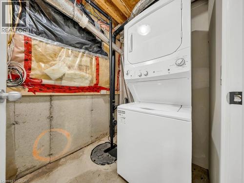 Dedicated utility area featuring a white stackable washer and dryer unit, concrete foundation walls, exposed overhead ductwork, and a visible sump pump - 39 Baintree Way, Cambridge, ON - Indoor Photo Showing Laundry Room