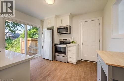 Modern kitchen featuring stainless steel appliances, white cabinetry, and wood-finish flooring - 55 Rex Drive, Kitchener, ON - Indoor Photo Showing Kitchen