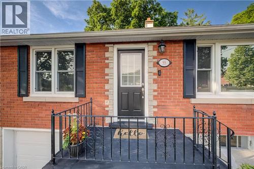 Brick exterior featuring decorative stone accents, white window frames, black louvered shutters, and a black front door with an integrated glass panel - 55 Rex Drive, Kitchener, ON - Outdoor With Exterior