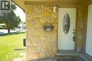 Stone veneer facade with a white entry door featuring an oval decorative glass insert, complemented by an exterior wall sconce - 136 Jansen Avenue, Kitchener, ON  - Outdoor 