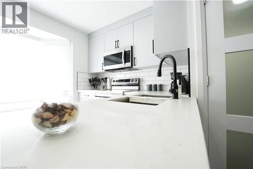 Sleek kitchen featuring expansive white countertops, a deep undermount sink with a matte black faucet, and white subway tile backsplash - 136 Jansen Avenue, Kitchener, ON - Indoor Photo Showing Kitchen