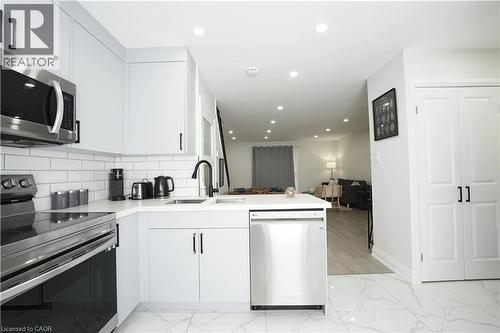 Modern kitchen featuring white cabinetry, subway tile backsplash, stainless steel appliances, and a matte black faucet - 136 Jansen Avenue, Kitchener, ON - Indoor Photo Showing Kitchen With Upgraded Kitchen