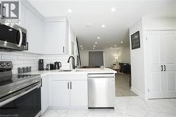 Modern kitchen featuring white cabinetry, subway tile backsplash, stainless steel appliances, and a matte black faucet - 