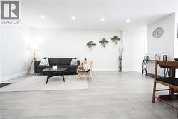 Spacious living area featuring light wood-finish flooring, recessed lighting, and white baseboards - 