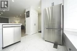 Kitchen featuring stainless steel appliances, white cabinetry, and white tile flooring - 